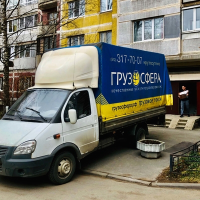 Мужчина несет ручную поклажу в открытый кузов газели