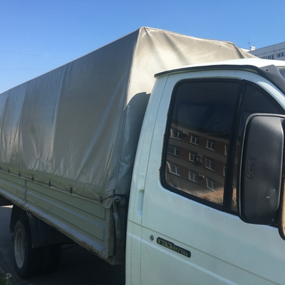 В окне грузового такси отражается дом