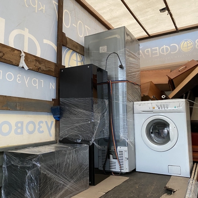 Стиральная машина и другая бытовая техника стоят в кузове грузовика