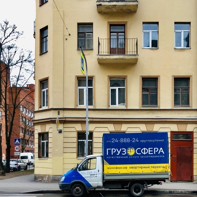 Грузовое такси стоит возле желтого здания с красной дверью