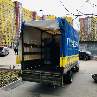 Открытый кузов газели во дворе с желтыми многоэтажками